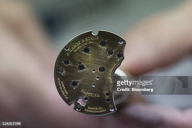 An employee holds a three-quarter plate for a luxury wristwatch during manufacture inside the A. Lange & Soehne factory, operated by Cie. Financiere...