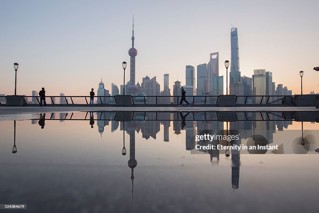 Shanghai skyline at sunrise reflected in water