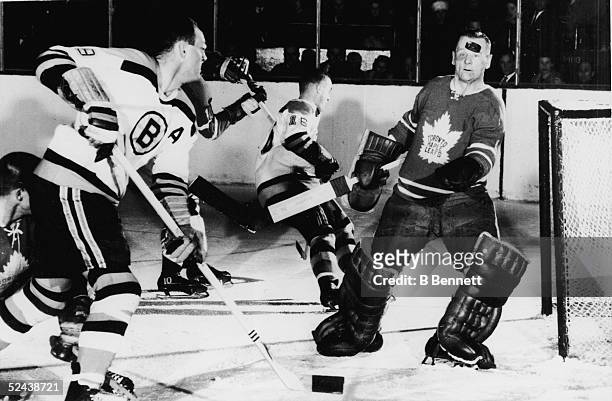Goalie Johnny Bower of the Toronto Maple Leafs keeps his eyes on an airborne puck shot by Doug Mohns of the Boston Bruins during their game at Maple...