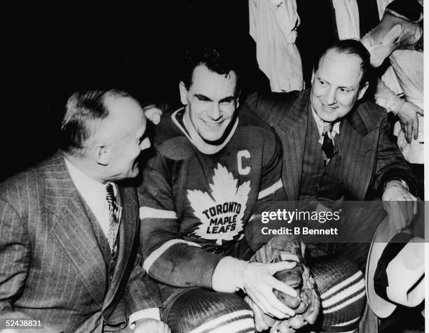 Head coach C.H. Day, Syl Apps and team manager Conn Smythe of the Toronto Maple Leafs celebrate in the locker room after their Stanley Cup victory...