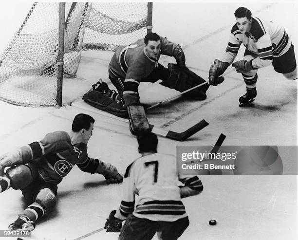 Canadian professional ice hockey player Jacques Plante goalie of the Montreal Canadiens and teammate Butch Bouchard combine forces to prevent a goal...