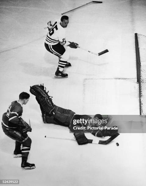 Canadian professional ice hockey player Jacques Plante goalie of the Montreal Canadiens dives to prevent a goal during a game against the Chicago...