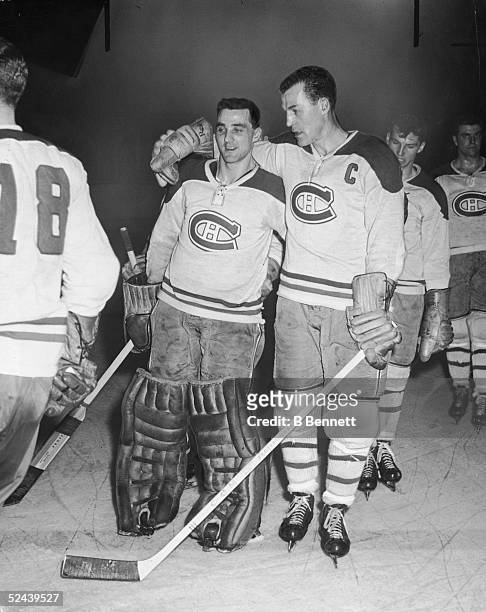 Canadian professional ice hockey players goalie Jacques Plante and Butch Bouchard of the Montreal Canadiens stand with their arms around each other...