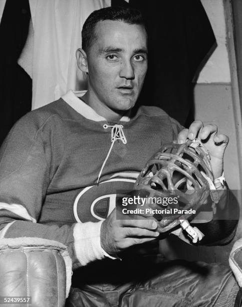 Canadian professional ice hockey player Jacques Plante goalie of the Montreal Canadiens sits in the locker room and shows his mask, September 30,...