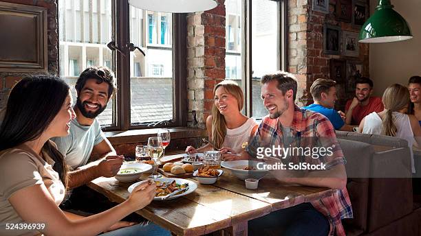 friends enjoying a meal - gastro pub stock pictures, royalty-free photos & images