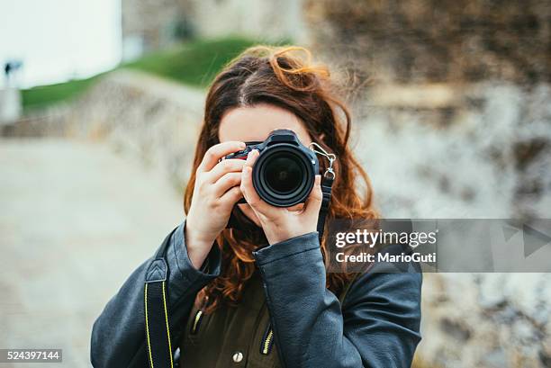 junge frau mit dslr-kamera - spiegelreflexkamera stock-fotos und bilder