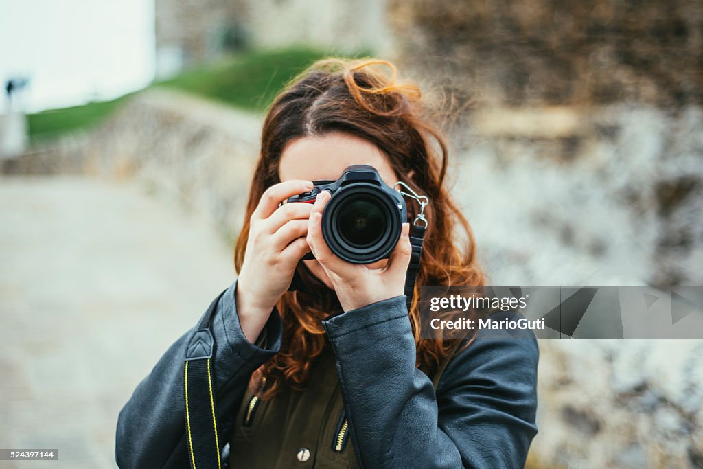 Mujer joven usando cámara RÉFLEX DIGITAL