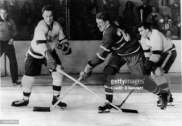 Canadian hockey player Red Kelly of the Detroit Red Wings battles with Paul Masnick of the Montreal Canadiens for an airborne puck while Red Wing...