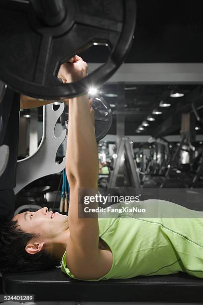 young man in gym lifting weight, side view - weight bench stock pictures, royalty-free photos & images