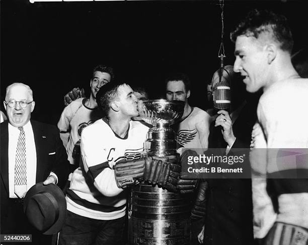 Canadian hockey player Ted Lindsay of the Detroit Red Wings hugs and kisses the Stanley Cup following his team's victory in the finals, 1954. Just...