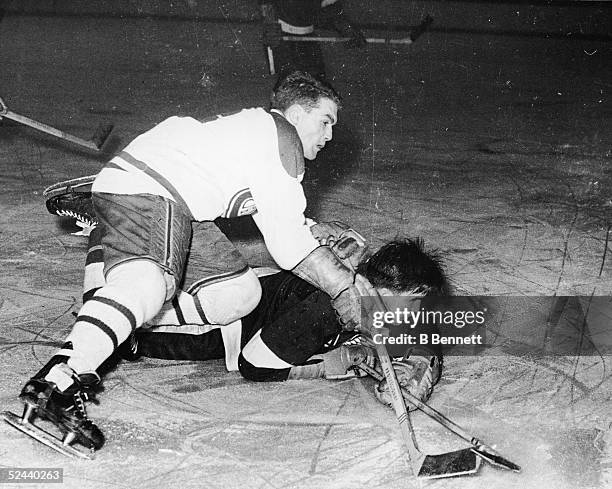 Canadian hockey player Henri Richard of the Montreal Canadiens and Marty Pavelich of the Detroit Red Wings struggle for the puck during a game, early...
