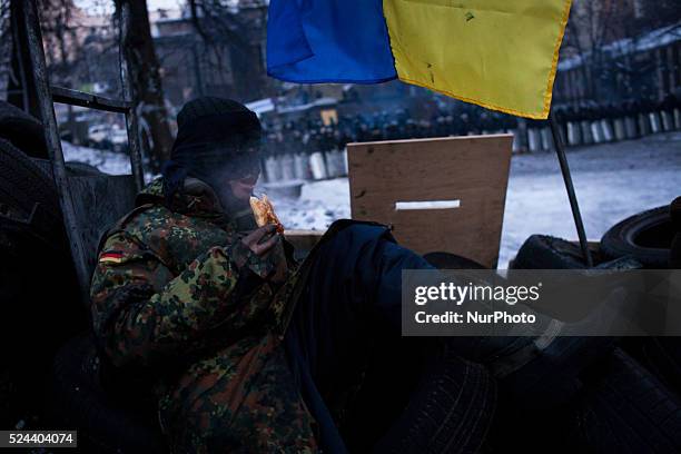 Anti-government protesters sits on the tires at the barricades and eat lunch in front of the police , the site of the fiercest recent clashes with...