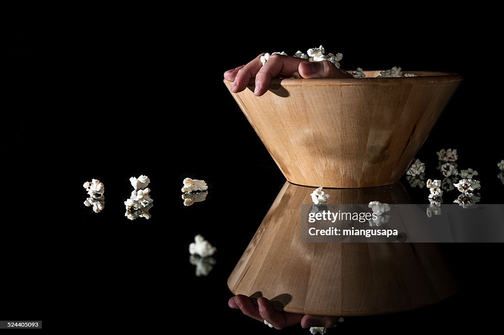 Hand out of a bowl of popcorn