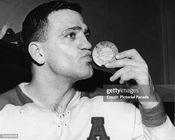 Canadian professional hockey player Bernie 'Boom Boom' Geoffrion of the Montreal Canadiens kisses a National Hockey League puck for some reason,...