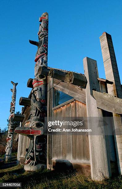 Totem poles stand outside a longhouse in the Haida village of Old Masset, on Queen Charlotte Islands, in British Columbia, Canada. The Haida...