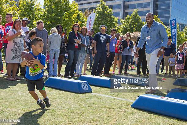 Cowboys legend Darren Woodson throws pass to a young fan during a football drill at Carnival's Ultimate Cowboys Fan Fest on October 18, 2015 at Klyde...