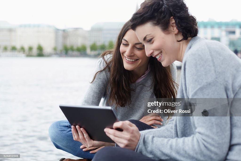 Two young women using digital tablet outdoors