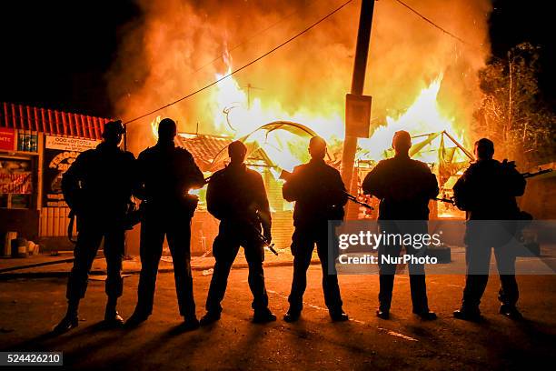 Separatists soldiers posing in front of a shop in fire destroy by an heavy artillery shoot from the ukrainian army, on May 22, 2014.