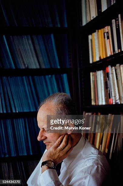 German-American nuclear physicist Hans A Bethe deep in thought as he sits surrounded by book-lined shelves in a library, circa 1955.