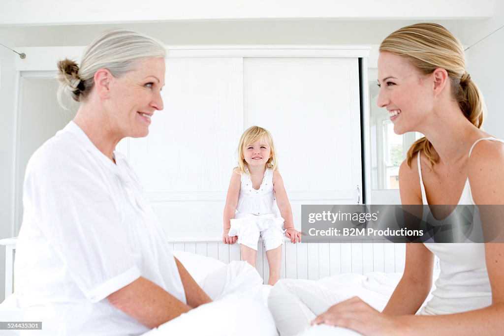 Grandmother, mother and girl (3-4) playing on bed