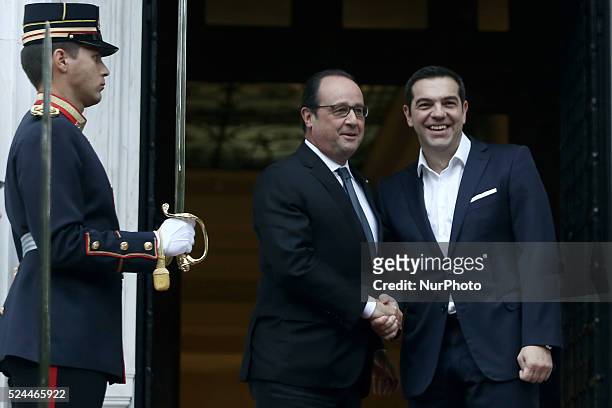 Greek prime minister Alexis Tsipras welcomes French President Francois Hollande prior to their talks at Tsipras' office in Athens on October 23,...