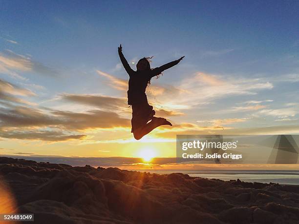 young woman leaping into the air at sunset - jumping sun stock pictures, royalty-free photos & images