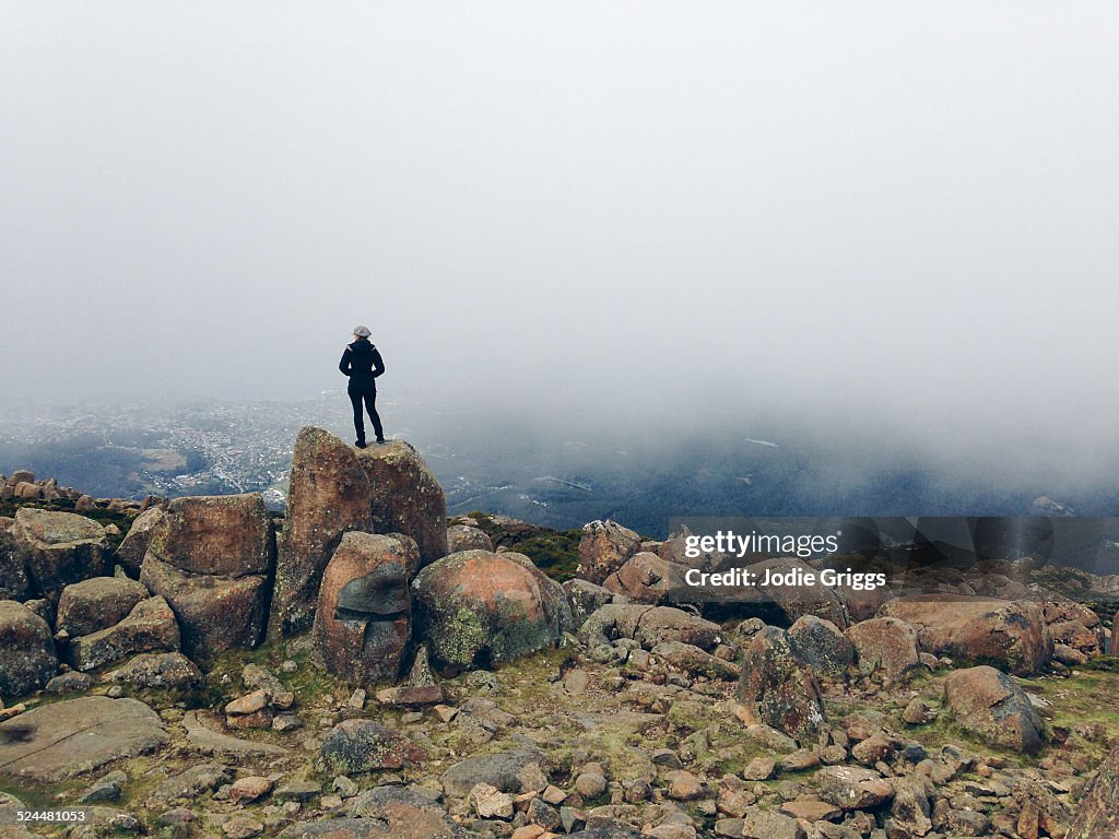 Woman standing on mountain top looking out at city