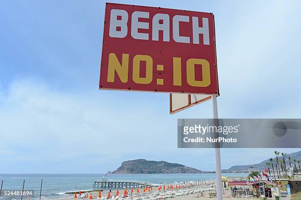 Sign with a general view of the Alanya beach, and walls and landward fortress of Alanya Castle in the background. Alanya, Turkey, on April 25, 2015.