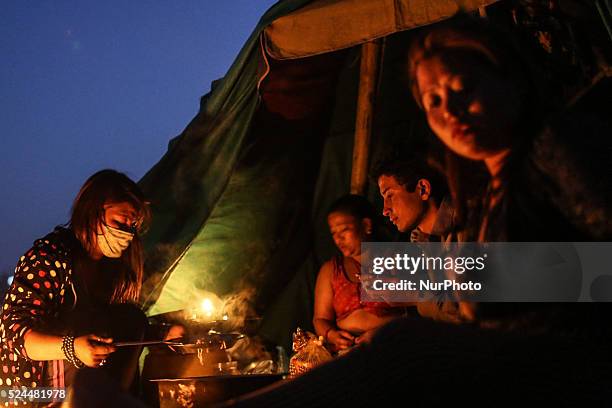 Woman is cooking and family members are waiting for the dinner in front of their tent at Tudikhel temporary shelter, Kathmandu, 2nd May 2015. The...