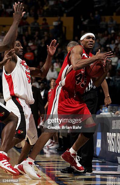 Brian Hamilton of the Louisiana-Lafayette Ragin' Cajuns calls time-out while guarded closely by Taquan Dean of the Louisville Cardinals in the first...