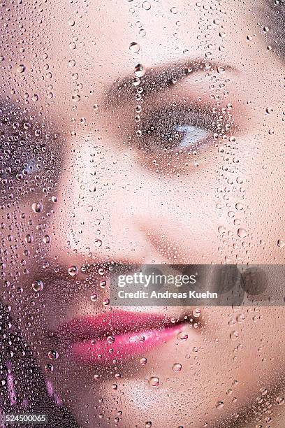 young woman's close up behing glass with droplets. - water repellent stock pictures, royalty-free photos & images