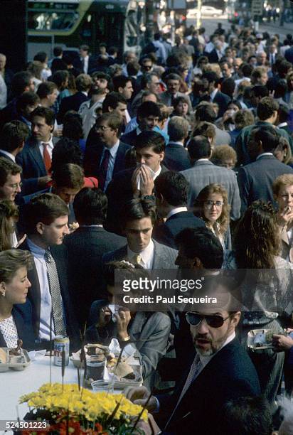 Large crowd of people sit and stand on Adams Street, outside the Berghoff Restaurant, during OctoberFest, Chicago, Illinois, 1980s.
