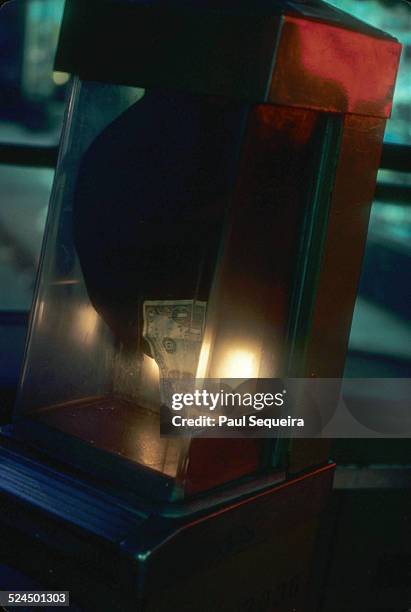 View of a dollar bill inserted into an old fare box on a city bus, Chicago, Illinois, 1980s.