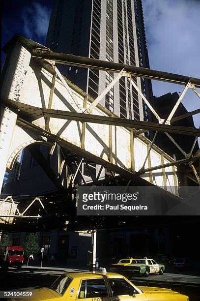 View of taxi cabs and a truck at an intersection located below the elevated subway tracks in the downtown Loop neighborhood, Chicago, Illinois, late...