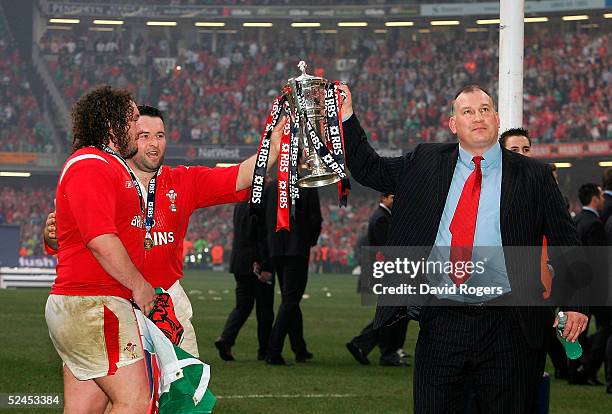 Mike Ruddock the Wales coach together with players Adam Jones and Mefin Davies raise the trophy as Wales' win the Grand Slam after defeating Ireland...