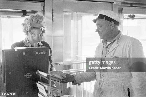 Customer paying as he leaves Johnny's Diner, with the cashier smiling as she hands him his change, in Somerville, New Jersey, 1950.