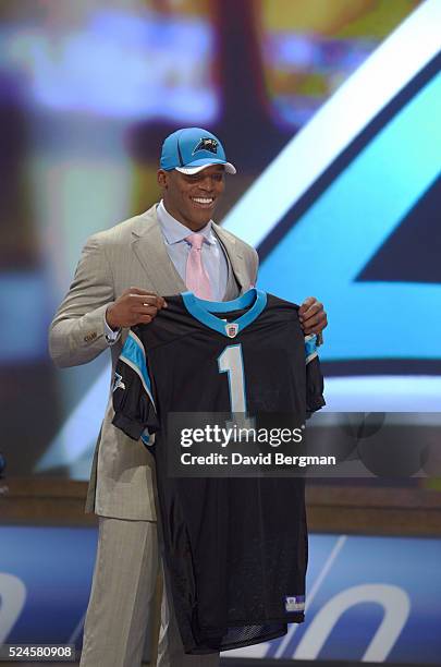 Carolina Panthers QB and No 1 overall pick Cam Newton victorious, holding jersey on stage during selection process at Radio City Music Hall. New...