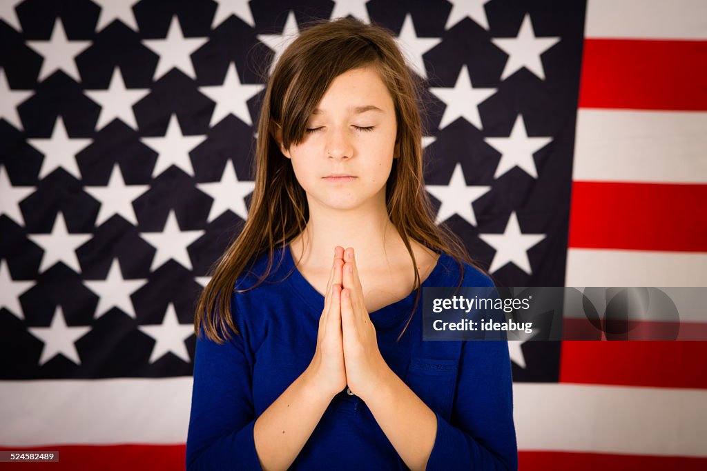 若い Preteen Christian ガールの前で祈るアメリカの国旗