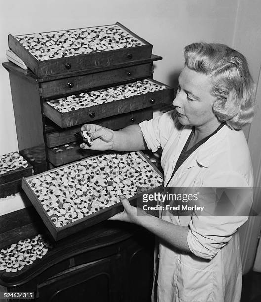 Mollie Surman of Kingston in Surrey with her stock of glass eyes, 18th July 1957. Mrs Surman makes the eyes herself, a craft passed down to her by...