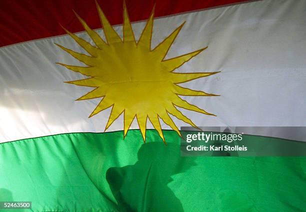 Kurdish man is silhoutted against the Kurdish flag during a Kurdish New Year celebration March 20, 2005 in Lake Dallas, Texas. The area is home to...