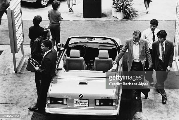 Visitors inspecting a BMW 325i car at the New York International Auto Show at the Jacob Javits Convention Center, New York City, USA, April 1987.