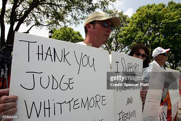 Supporters of Michael Schiavo, husband of brain-damaged Florida woman Terri Schiavo, hold signs in front of the Woodside Hospice where brain-damaged...