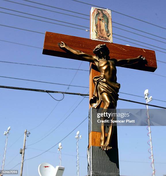 Crucifix competes with a sky of television satellite antennas in front of the Woodside Hospice where brain-damaged Florida woman Terri Schiavo is...