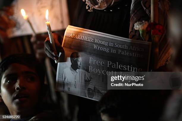 Palestinian woman holds a candle and a picture for The late Nelson Mandela during a candles pause to honor The former president of South Africa in...