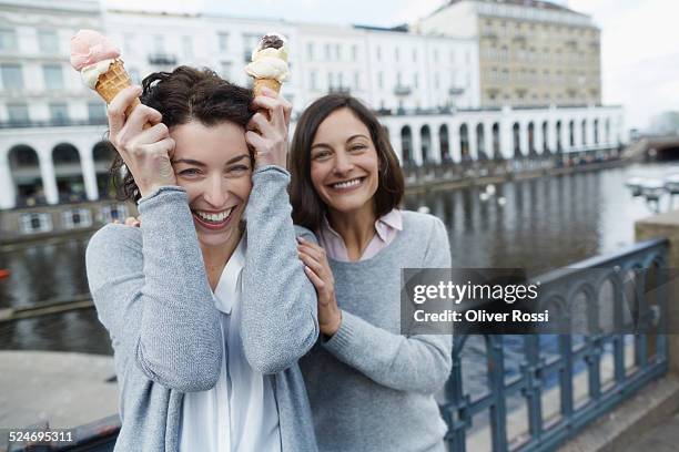 two playful young women eating ice cream - elbe river stock pictures, royalty-free photos & images