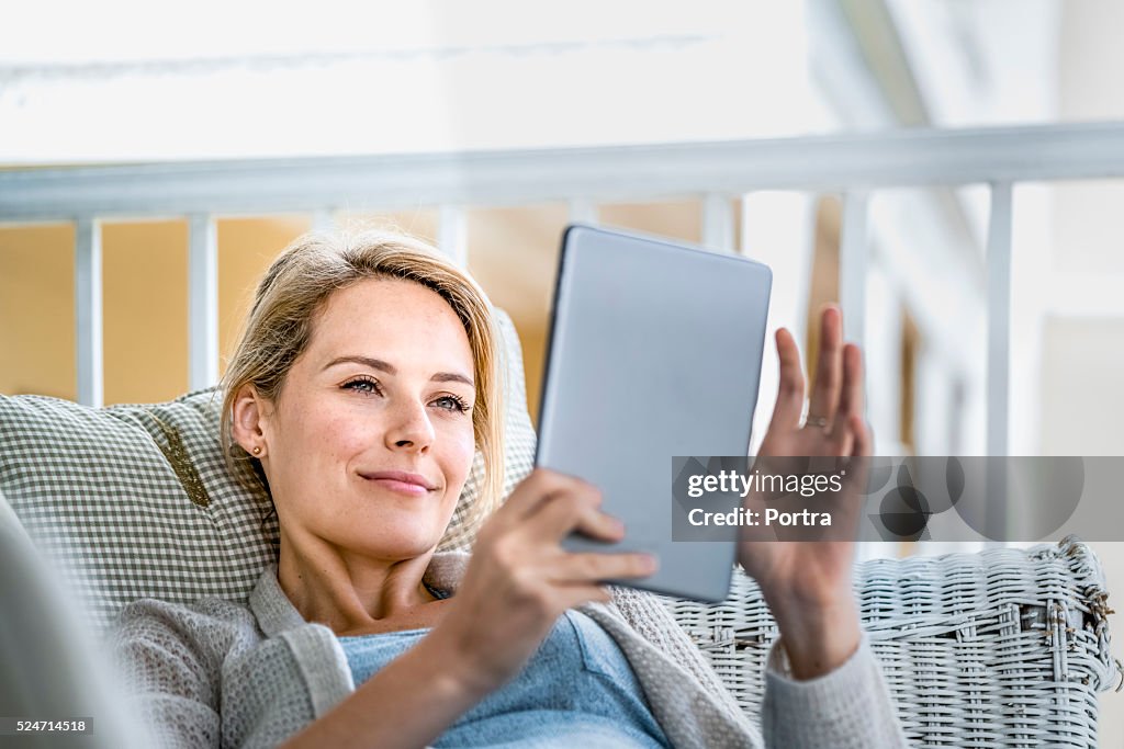 Glücklich junge Frau benutzt Digitaltablett auf Balkon