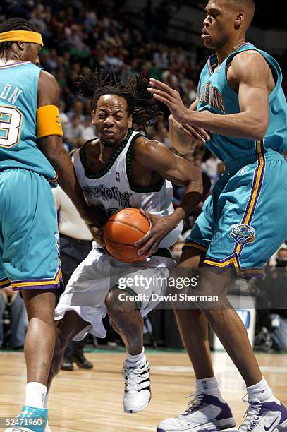 Troy Hudson of the Minnesota Timberwolves drives to the basket against Lee Nailon and Jamaal Magloire of the New Orleans Hornets on March 23, 2005 at...