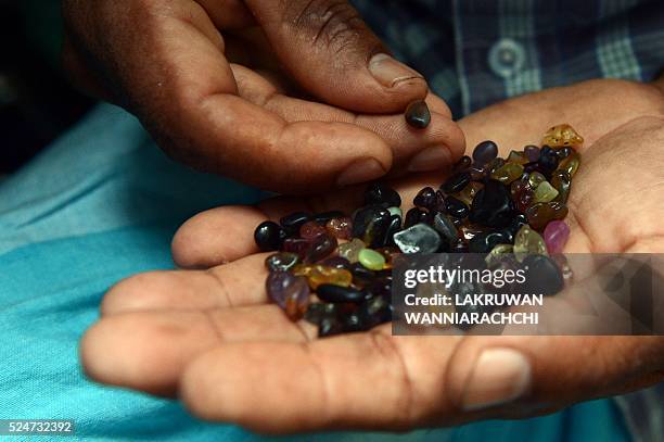 In this photograph taken on February 17 a Sri Lankan gem dealer holds a palmful of rough precious and semi precious stones in Ratnapura district,...