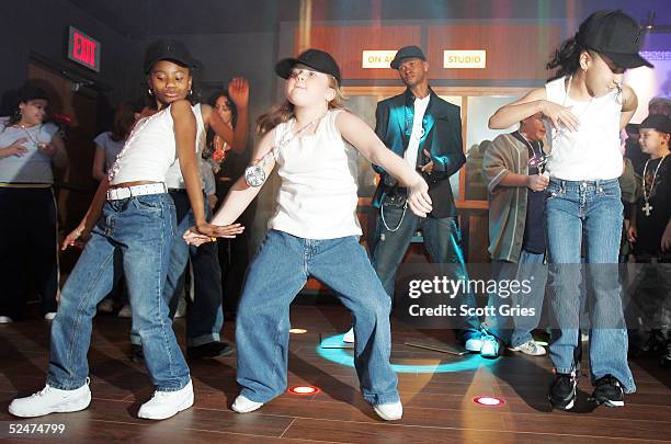 Children sing and dance along side the new wax figure of R & B singer Usher during a competition to launch the Usher Interactive Experience at Madame...