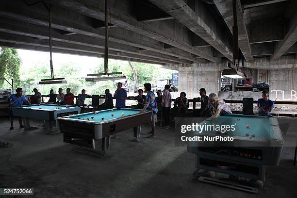 January 12 : Indonesian men playing billiards under a bridge at slum area in Jakarta, Indonesia, on January 12, 2016. A players pay 2,000 IDR for...